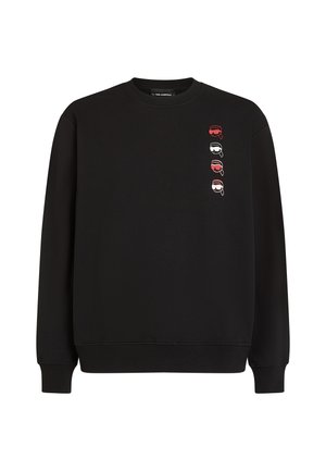Sort sweatshirt med lange ærmer, der har en vertikal linje af fire trykte ansigtstræk i rød, sort og hvid på forsiden. Blødt stof, afslappet pasform.