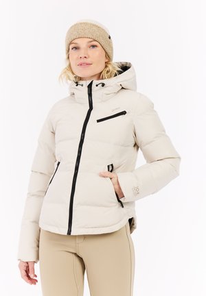 Witte gewatteerde jas met capuchon, zwarte ritsen, elastische manchetten en een ritsvak op de borst. Draag het met een beige gebreide muts.