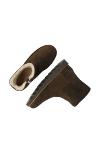 Botas de tobillo de ante marrón con un suave forro crema y una suela de goma texturizada. Presenta una cremallera lateral para facilitar el uso.