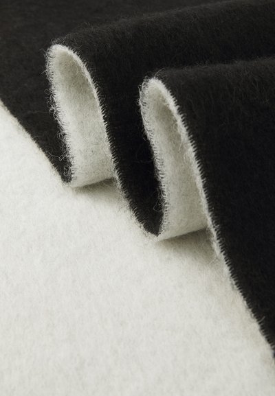 Felt fabric in black and white, featuring a soft texture with subtle fibers. The edges are stitched, showing clean, contrasting colors.