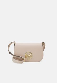 Beige kožená crossbody taška se zlatým kruhovým logem, s vrchním klopovým uzávěrem a odnímatelným popruhem. Hladká textura, kompaktní design.