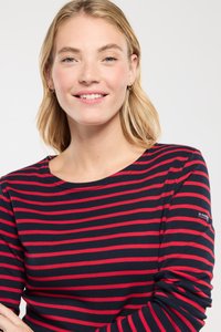 Langærmet bomuldsbluse med marineblå bund og røde horisontale striber, rund halsudskæring og et lille logo på ærmet.