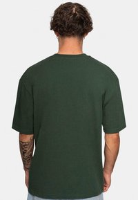 Grøn bomulds t-shirt med en afslappet pasform, korte ærmer og rund hals, som viser en glat tekstur og ingen synlige logoer eller mønstre.