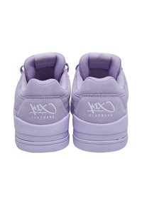 Violet zomšiniai sportbačiai su lygiu guminiais padu, paminkštintu apykakle ir baltu logotipu gale. Suapvalinta forma su minimaliais dizaino elementais.