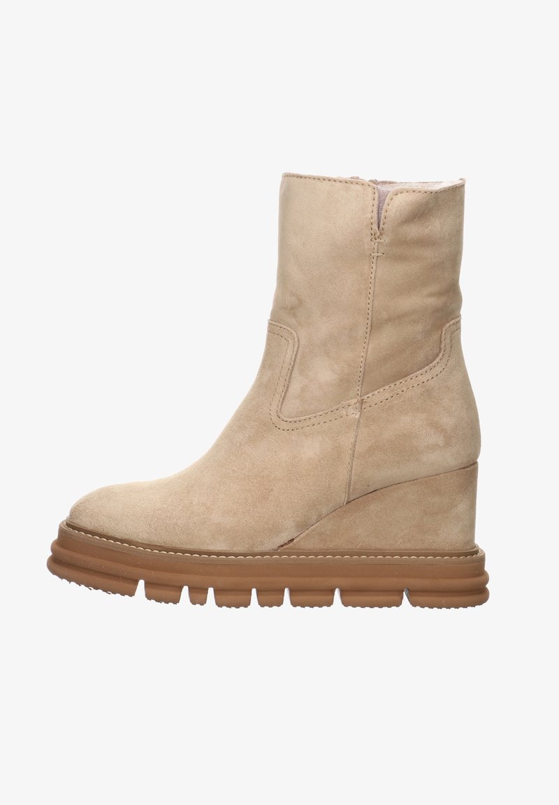 Botte mi-mollet en suède beige avec une semelle épaisse à crans marron et un talon en forme de coin, présentant des coutures visibles et une fermeture éclair sur le côté.