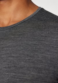 T-shirt cinza em algodão com decote redondo. O tecido tem uma textura subtil e um ligeiro brilho, sem padrões ou elementos em destaque visíveis.