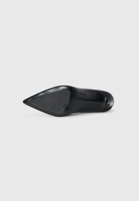 Black pointed-toe high heel shoe viewed from the sole with smooth surface and small heel tip on a white background.