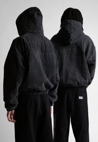 Tamsiai pilka gobtuvinė sportinė palaidinė su elastingomis rankovėmis ir apačia, rodanti iškilų "Wasted" logotipą ant nugaros. Dėvima su juodomis sportinėmis kelnėmis.