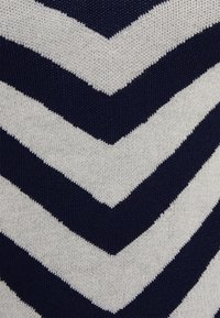 Dzianina o wzorze w navy i białe zygzaki w stylu chevron. Tekstura jest gładka, z drobnymi ściegami i lekkim odczuciem.