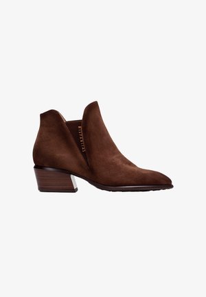 Bottines en suede marron avec un orteil pointu, un petit talon carré et des côtés découpés. Présentent une texture lisse et un accent en bois sur le talon.