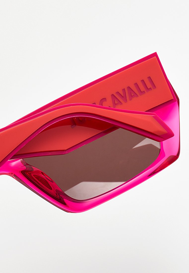 Lunettes de soleil géométriques roses vives avec des verres marron et une branche orange ornée d'une marque de créateur en relief.