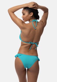 Tirkīza krāsas bikini ar kakla siksnu, ievilkumiem kaklā un aizmugurē, kā arī ruffles apakšdaļas malās. Gluda tekstūra, minimālisma dizains.