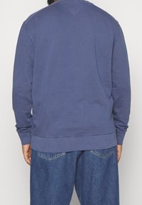 Felpa a manica lunga con scollo rotondo in tessuto blu tinta unita, caratterizzata da polsini e orlo a coste, con una vestibilità comoda e un design semplice.