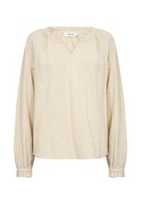 Blouse beige en tissu doux, avec un col en V, des manches longues bouffantes et des broderies décoratives le long de l'avant et des poignets.
