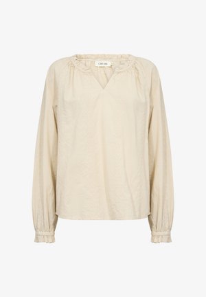 Beež pluus pehmest kangast, millel on V-kaelus, puhvis pikad varrukad ja dekoratiivne tikand ees ja mansettidel.