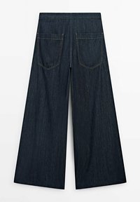 Pantalons en denim bleu foncé à jambes larges avec poches arrière et coutures visibles, présentés de dos sur un fond uni.