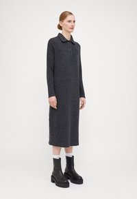 Rochie lungă de culoare gri cărbune, cu guler, detalii cu nasturi și o croială dreaptă, asortată cu cizme negre cu toc gros până la gleznă.