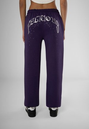 Purple sweatpants with an elastic waistband, featuring silver logo and rhinestone embellishments on the back, relaxed fit.
