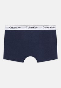 Námornícke modré bavlnené boxerky s bielym pásom so štítkom Calvin Klein v čiernej farbe. Hladká textura a klasický dizajn.