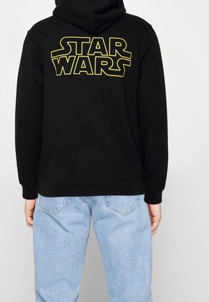 Black hoodie featuring a large yellow "STAR WARS" logo on the back. Material appears soft; design includes a kangaroo pocket and hood.