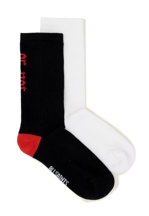 Yksi pari sukkia, toinen musta punaisella kantapäällä ja valkoisella tekstillä, toinen yksivärinen valkoinen, molemmat tasaisesti esillä ja osittain päällekkäin.