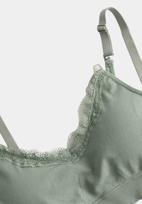 Zachte groene bralette met verstelbare bandjes en delicate kantafwerking langs de halslijn, gemaakt van gladde, rekbare stof.