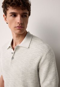 Hellgraues, strukturiertes Poloshirt mit Hemdkragen, 3-Knopfleiste und kurzen Ärmeln, mit einem gewebten Muster.