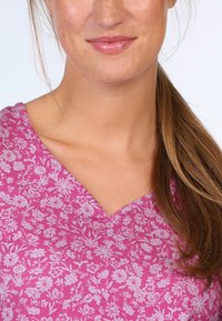 Magenta cotton top featuring a V-neck and floral print pattern in light pink. Smooth texture with short sleeves and relaxed fit.