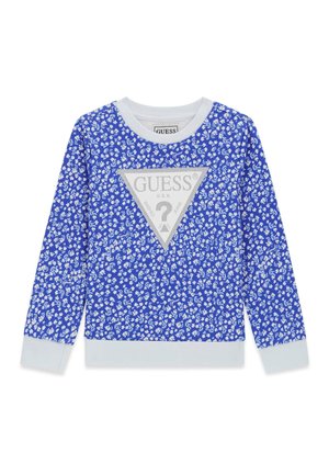 Niebieska koszula z długim rękawem z białym kwiatowym wzorem, białym kołnierzykiem i mankietami oraz dużym srebrnym trójkątem z logo Guess umieszczonym centralnie na przodzie.