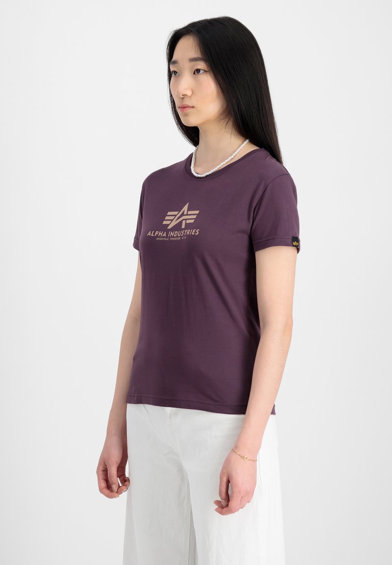 T-shirt bordeaux à manches courtes avec un col rond et un logo doré "ALPHA INDUSTRIES" à l'avant. Tissu doux, coupe slim.