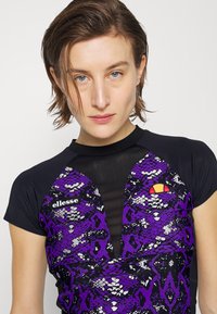 Lila und schwarze Rashguard mit Schlangenmotiv, kurzärmlig und mit Rundhalsausschnitt. Markenlogo auf der Brust.