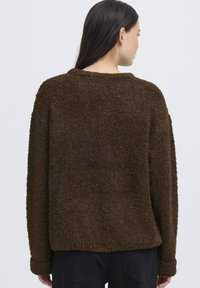 Maglione in pile marrone a texture con scollatura tonda e spalle scese, che mostra una vestibilità rilassata e un materiale morbido e peluche.