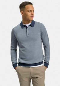 Marinblå polo shirt med texturerat mönster, långa ärmar och kontrasterande krage. Har knappslå samt ribbade muddar och nederkant.