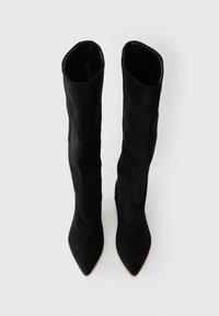 Black knee-high boots made of soft suede. Features pointed toes and a sleek, fitted design. Smooth texture with no visible hardware or patterns.