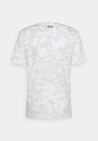 Camiseta de manga corta en gris claro con un patrón de camuflaje digital, presenta un cuello redondo y un logo en la parte superior de la espalda. Textura suave.