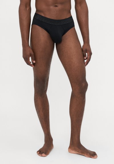 Black men's briefs made of smooth fabric, featuring a textured waistband. The design is snug with a contoured front.