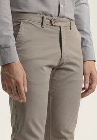 Chinos de color gris claro con una suave tela de algodón, que presentan un corte recto, bolsillos laterales y un cierre de botón único en la cintura.