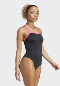 Zwarte badpak met roze bandjes, slank ontwerp en medium uitsnijding. Glad textuur met contrasterende accenten bij de halslijn en de bandjes.