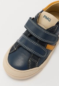 Pantofii din piele de culoare bleu marin cu accente de culoare piersică, curele Velcro, cusături în contrast și vârful rotund. Talpă din cauciuc cu un model texturat.
