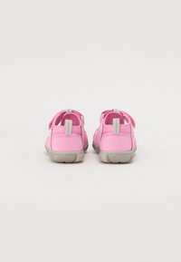 Pink shoes with a soft fabric upper and gray rubber sole. Features include adjustable straps and a padded heel for comfort.