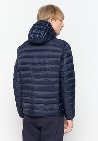 Námornícky modrá puffrová bunda s horizontálnym prešívaním, odnímateľnou kapucňou, hladkým syntetickým materiálom a elastickými manžetami.