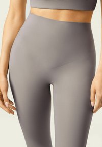 Legginsy o wysokim stanie wykonane z gładkiego, matowego szarego materiału. Charakteryzują się bezszwowym wzornictwem i dopasowanym krojem, podkreślającym talię i nogi.