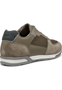 Zapatilla Geox en taupe con texturas de malla y ante, con suela de goma y una cubierta en el talón color gris. Cordones y logotipo visibles.