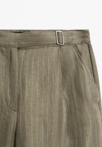 Olivově zelené kalhoty s proužky a texturovanou látkou, s bočními kapsami a stříbrnou kovovou sponou v pase.