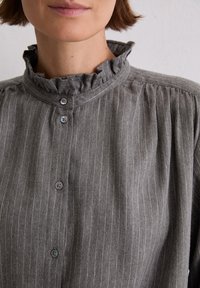 Grijze gestreepte blouse met een gerimpelde hoge kraag en knoopsluiting, gemaakt van textiel met een zachte afwerking.