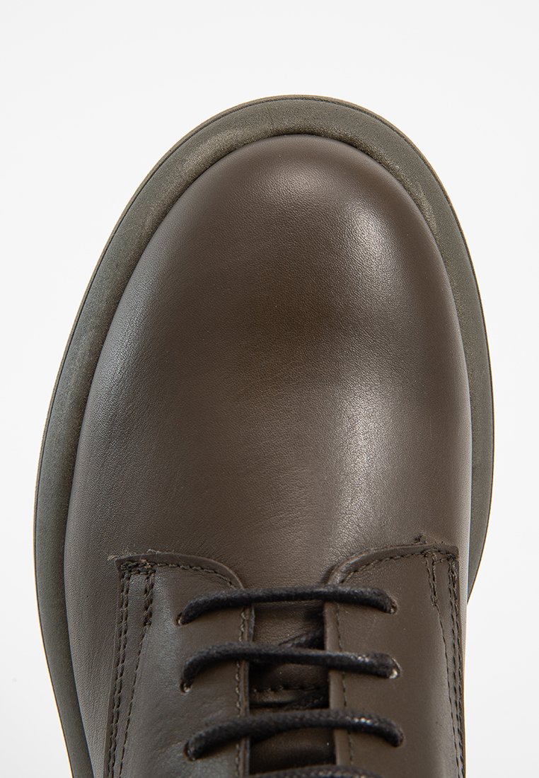 Brązowy skórzany but o gładkim wykończeniu, okrągłym nosku i czarnych sznurowadłach. Ma kontrastującą szaro-rubberową podeszwę oraz eleganckie detale w szyciu.