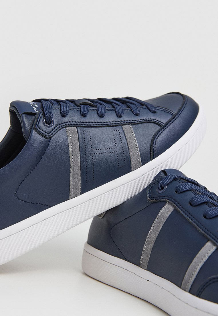 Baskets en cuir bleu marine avec des rayures latérales grises, des accents texturés et des semelles en caoutchouc blanc, dotées de lacets ronds et d'un logo sur la languette.