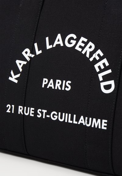 Черен текстилен сак с bold бял текст, изписващ "KARL LAGERFELD PARIS 21 RUE ST-GUILLAUME," с текстурирано покритие и структурирана форма.
