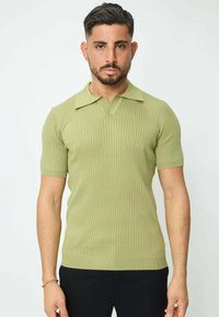 Polo à manches courtes, rayé, de couleur vert clair, avec un col classique et une coupe ajustée. Texture douce avec une légère élasticité.