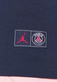 Námořnické bavlněné tričko s červeným vyšitým logem Jumpman a znakem Paris Saint-Germain s bílými a červenými akcenty.